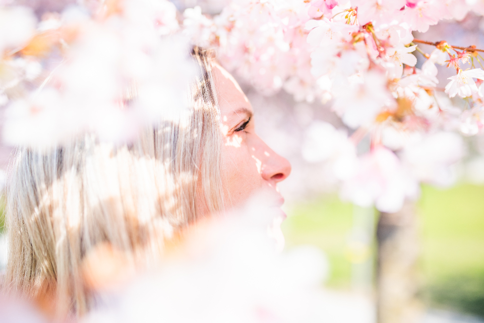 Mujer sonriendo rodeada de flores, símbolo de autocuidado y autoestima